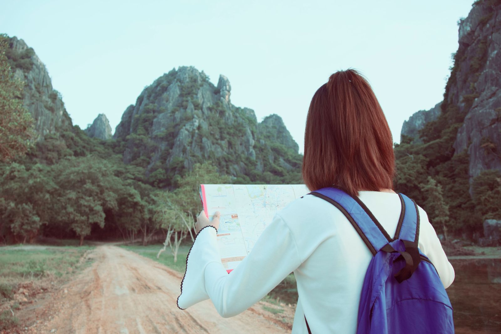 Una persona con una mochila morada consulta un mapa antes de continuar por un sendero entre montañas verdes